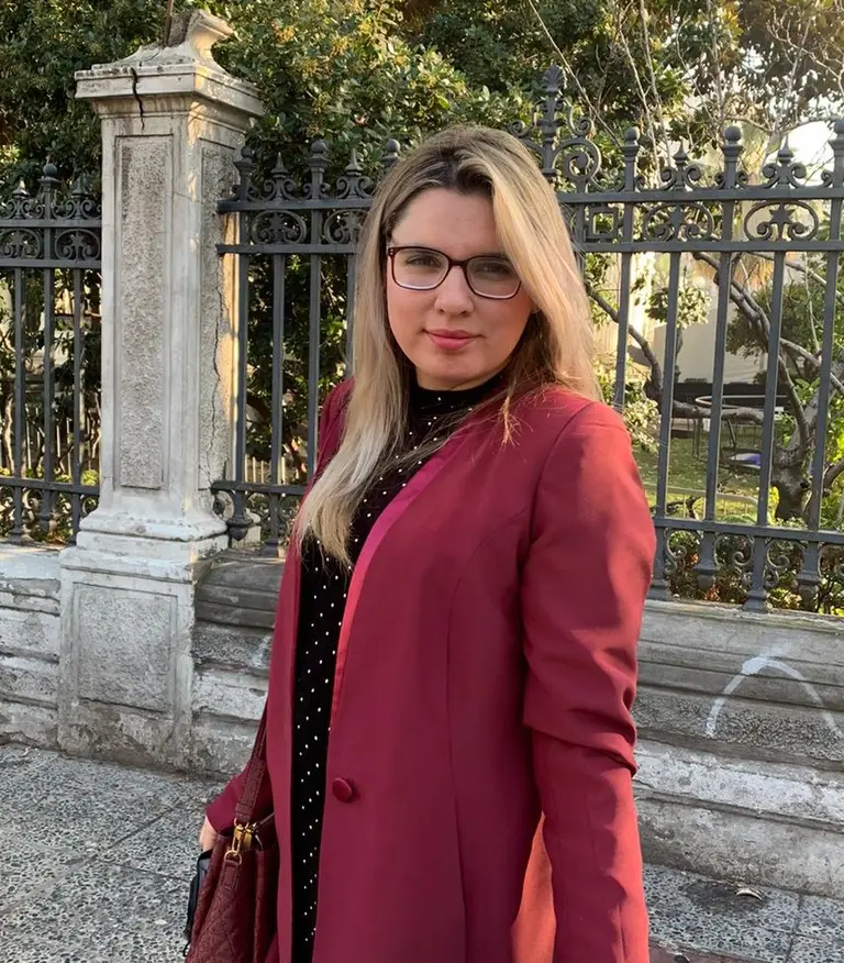 Mujer con abrigo burdeos posa en la calle.