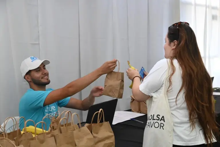 Voluntario entregando bolsas de comida en evento solidario.