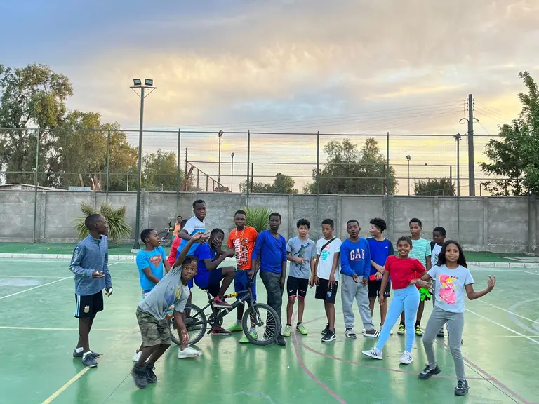 Niños jugando en cancha al aire libre.