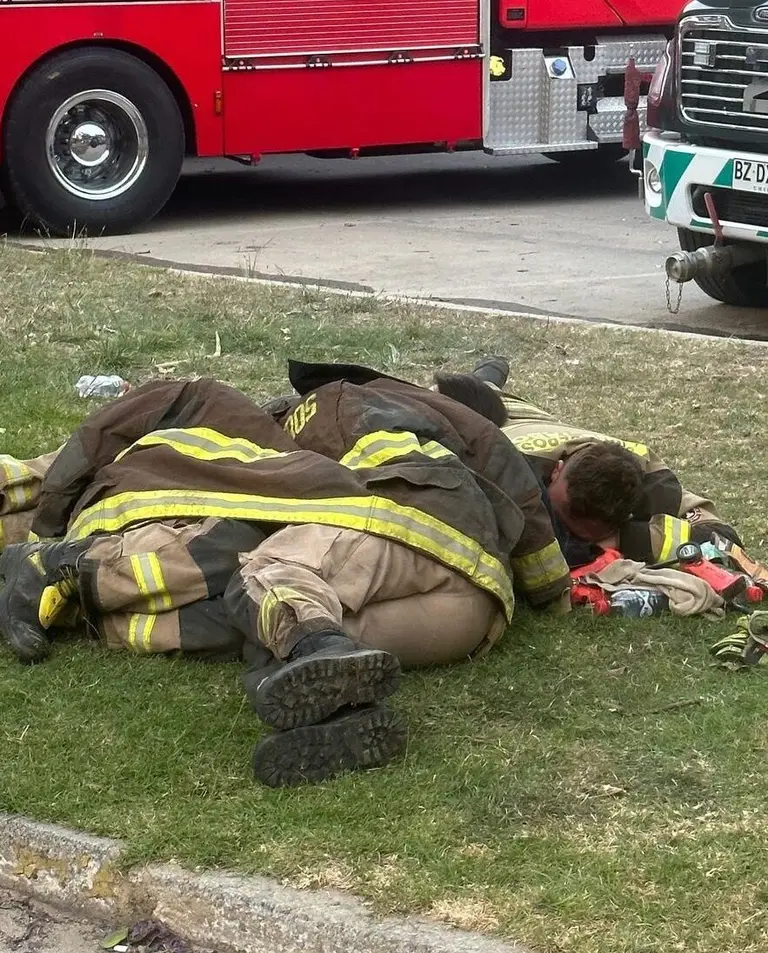 Bombero descansando en el césped junto a camión.