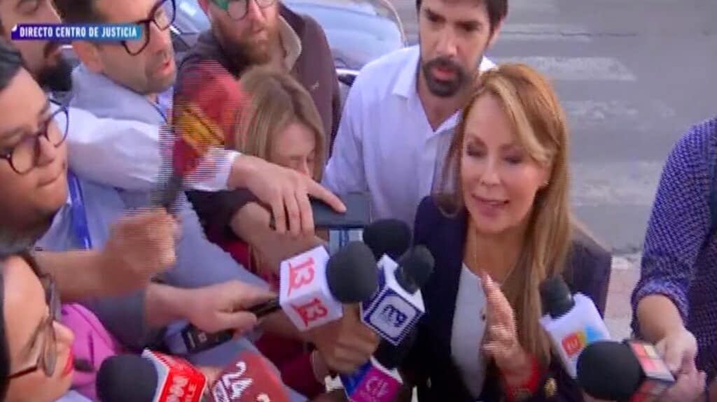 Cathy Barriga rodeada de periodistas con micrófonos.