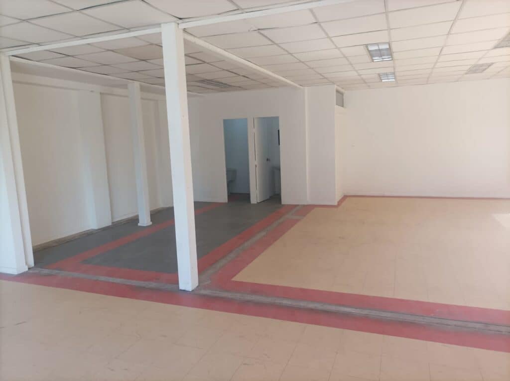 Oficina vacía con columnas y suelo de baldosas.