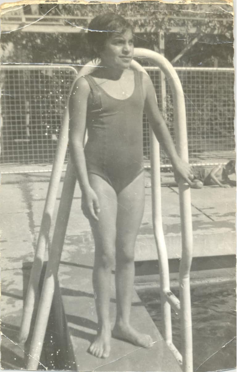 Niña en piscina con traje de baño vintage.