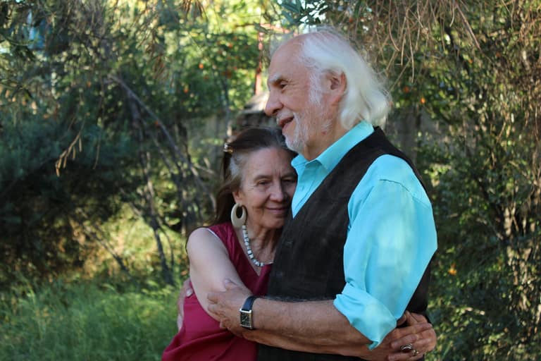 Pareja mayor abrazándose sonriente en la naturaleza.
