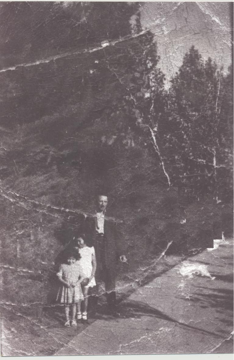Persona con niñas en paisaje montañoso antiguo.