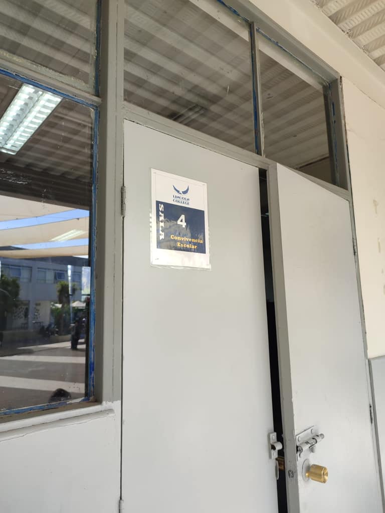 Puerta escolar con cartel de convivencia.