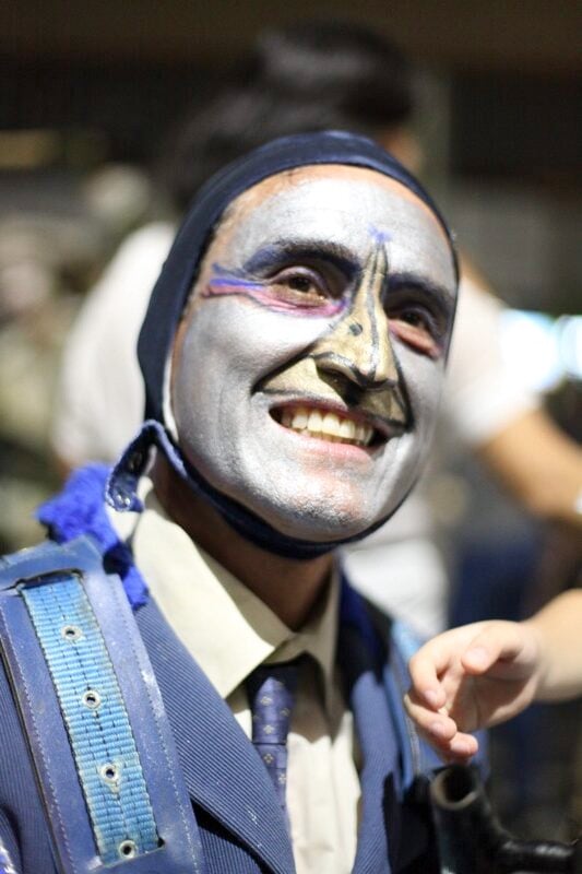 Persona con máscara pintada sonriente en evento.
