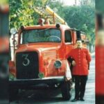 Bombero junto a camión rojo vintage.